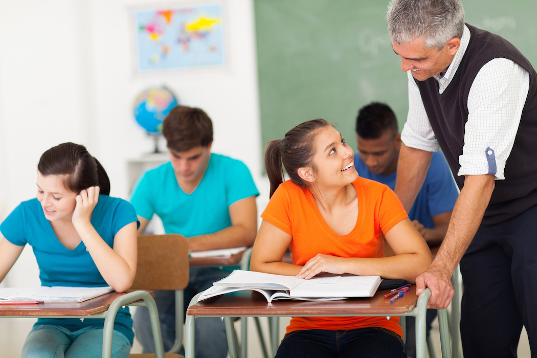 schuelerin blickt von ihrem buch zu lehrer auf